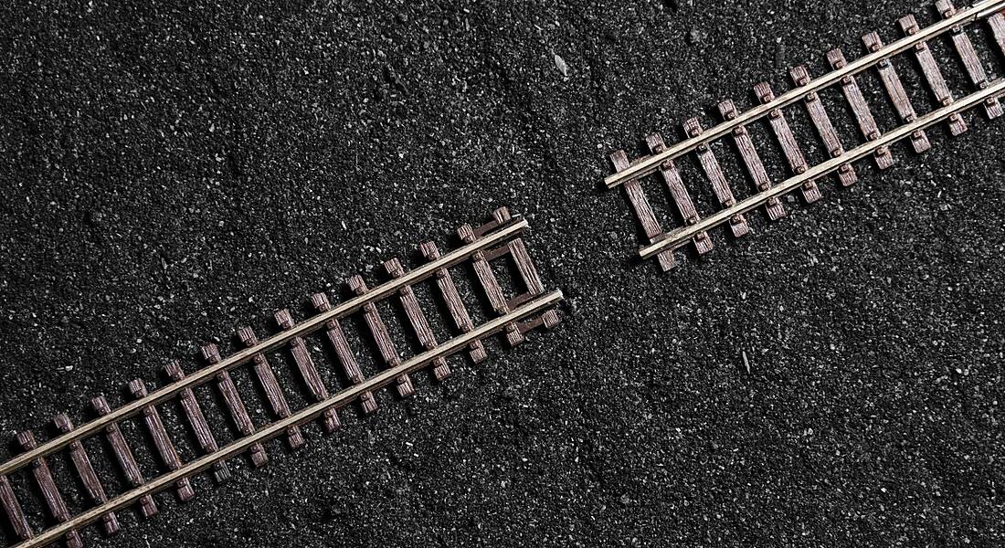 A gap in wooden railway tracks across a dark, gritty surface.