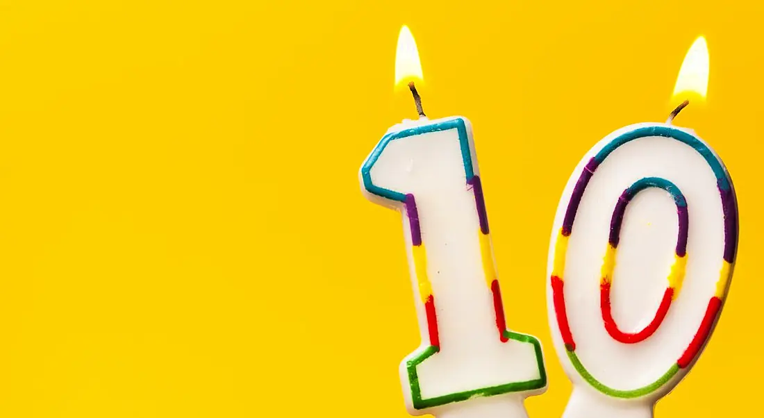 Number 10 birthday celebration candles against a bright yellow background.