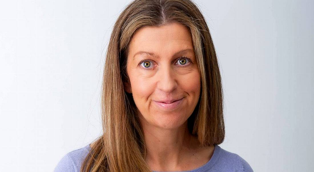 Erica Langhi is smiling into the camera and standing against a white background.