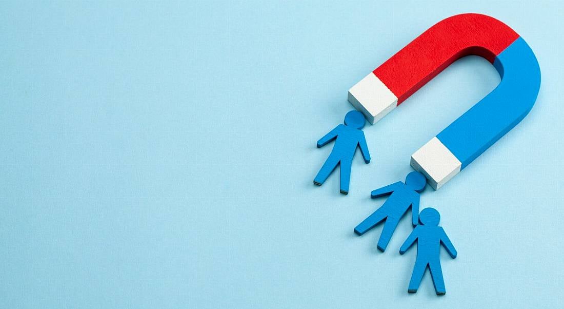 Magnet attracting small employees figures against a blue background.