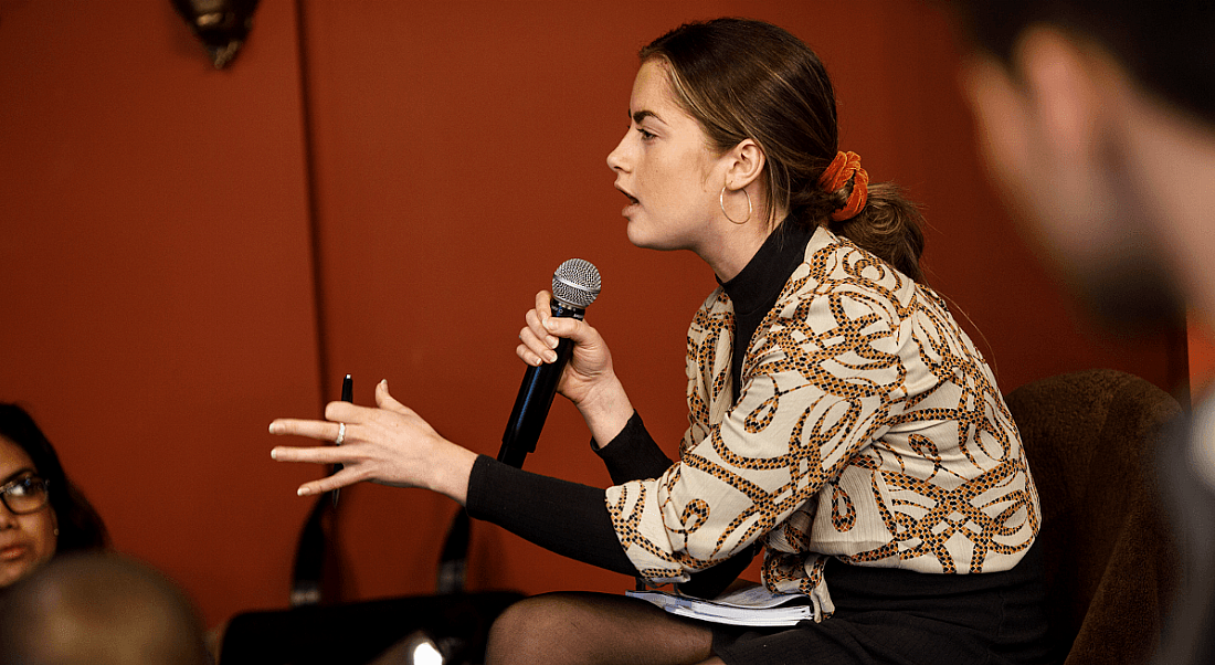 Kate Fuller is sitting and speaking into a microphone.