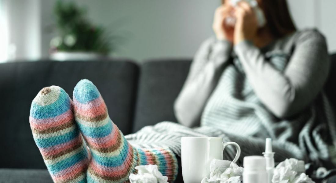 Sick woman with cold sitting on couch at home.