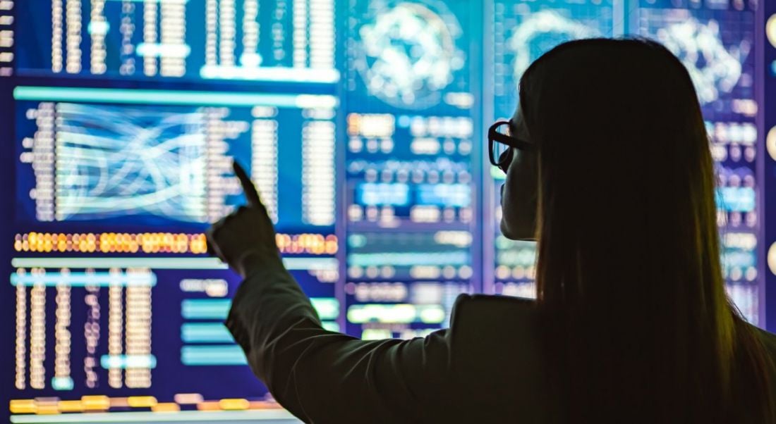 Silhouette of a woman interacting with data interfaces, symbolising data science skills.