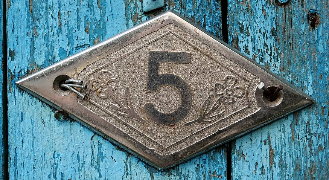 A blue wooden door with a sign reading number five on it.