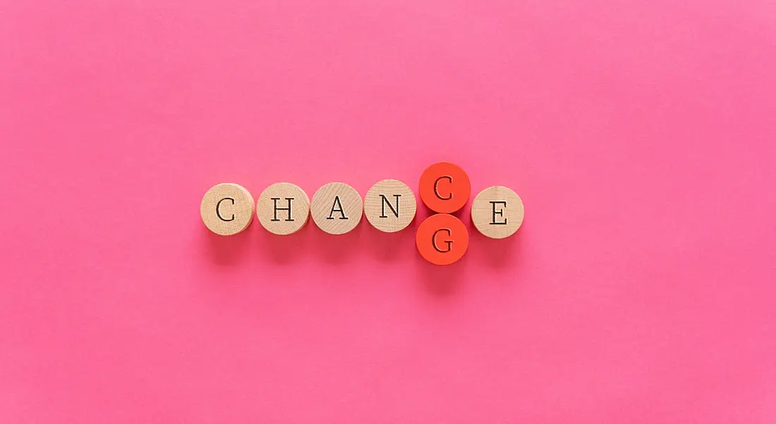 The word 'change' is spelled out on small wooden circles, with the letter G in red being pushed out by the letter C, changing the word to 'chance'.