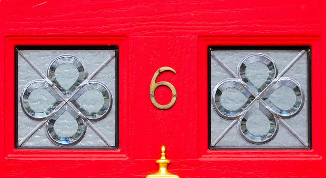 Bright red front door with square windows and a gold number six.