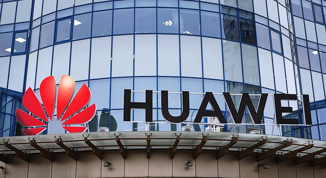 Huawei logo above the entrance to a glass office building.