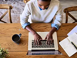 Young businesswoman looking deep in thought while sitting at her desk in a large modern office working online with a laptop.