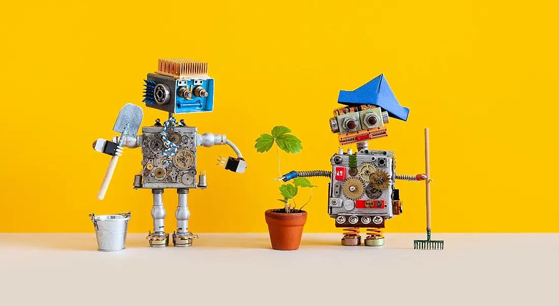 Two toy robots are staying connected and gardening together for their mental health against a yellow background.