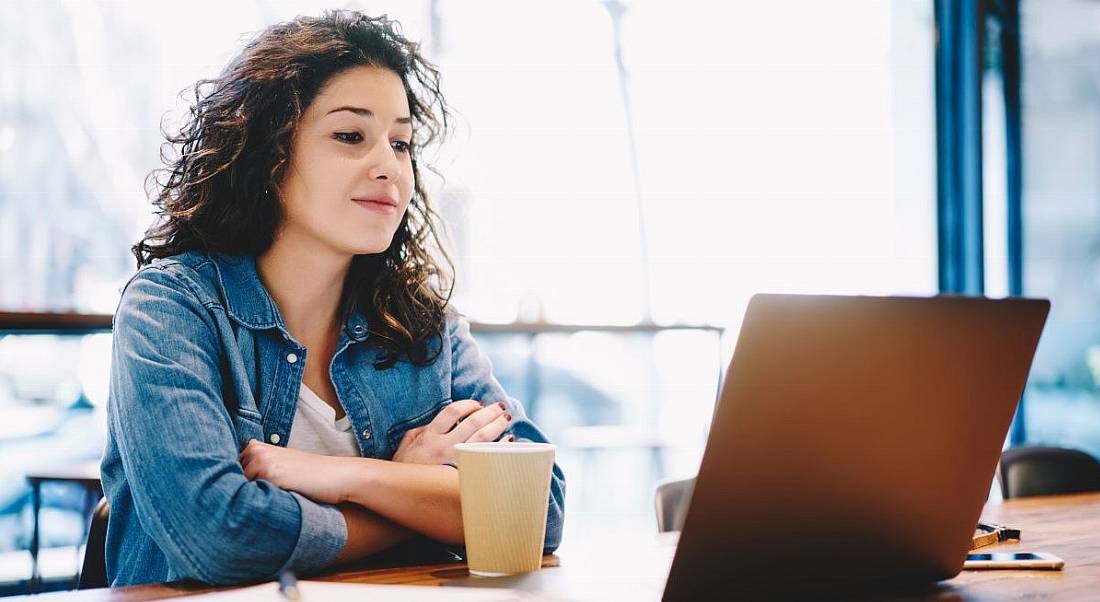 Women wearing an open denim shirt while sitting at a wooden table