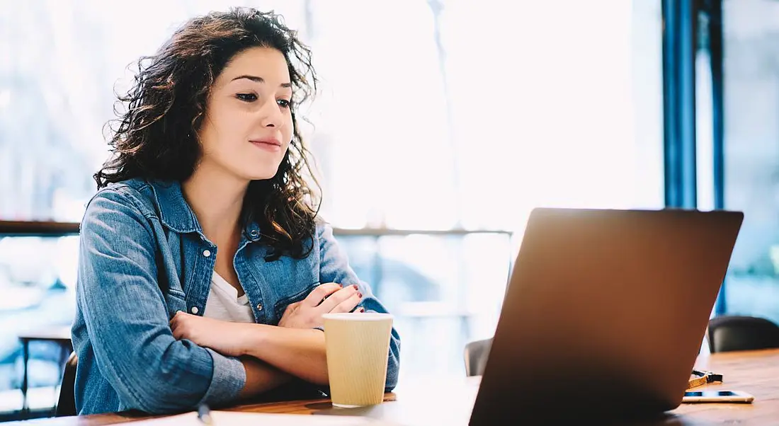 Women wearing an open denim shirt while sitting at a wooden table