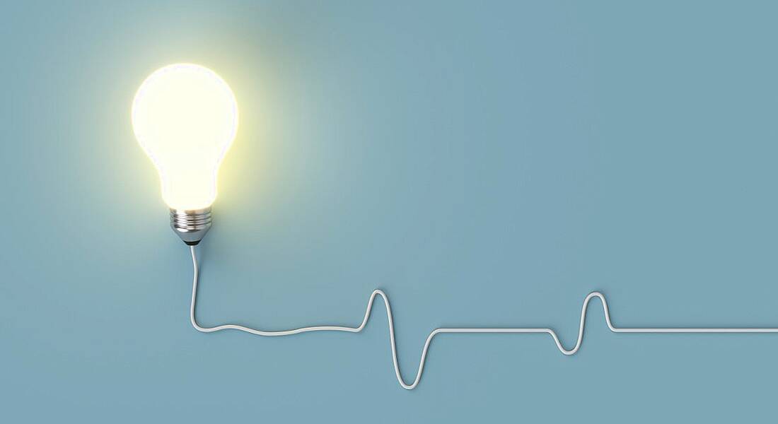 A lightbulb is lit up against a pale blue background.