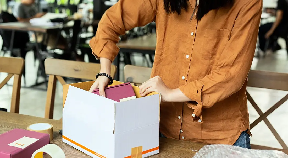 A woman is packing up her office belongings as she leaves her job.