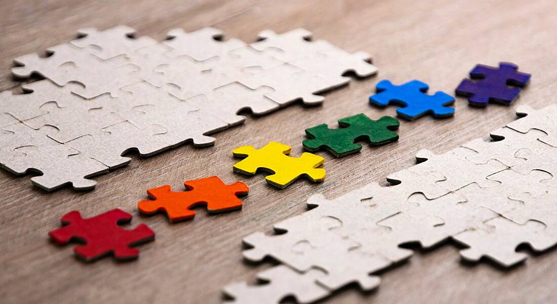 Colourful puzzle pieces are lined up on a wooden table, symbolising a diverse talent pipeline.