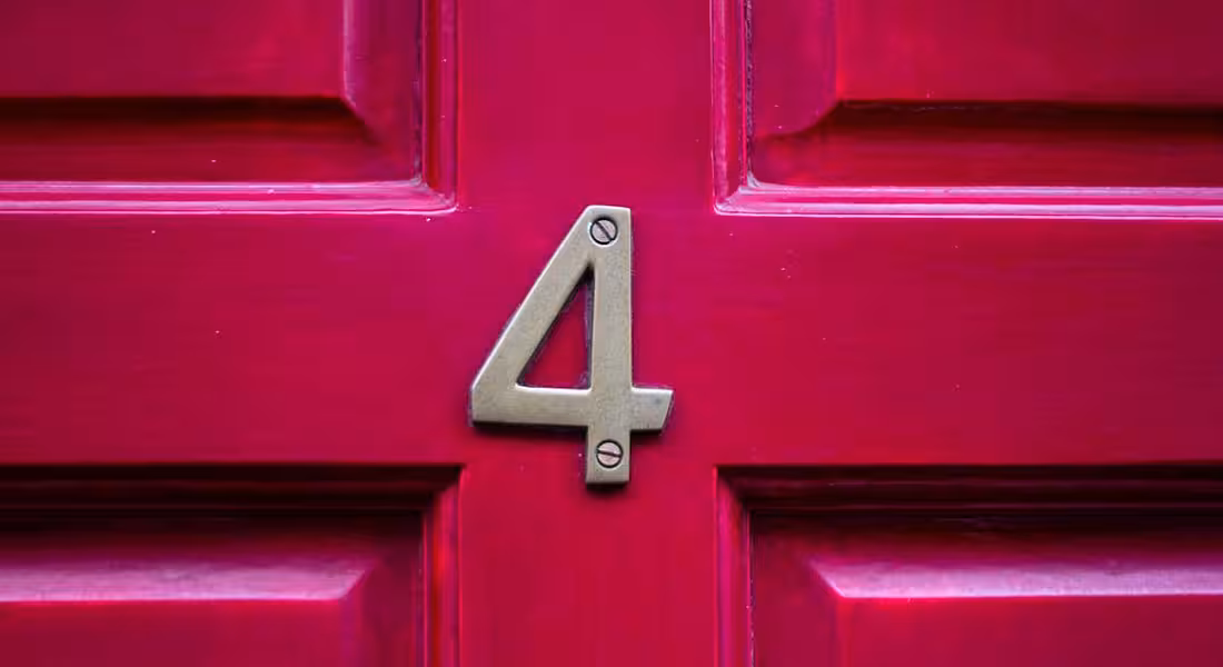 A red front door with a metal number four on it.