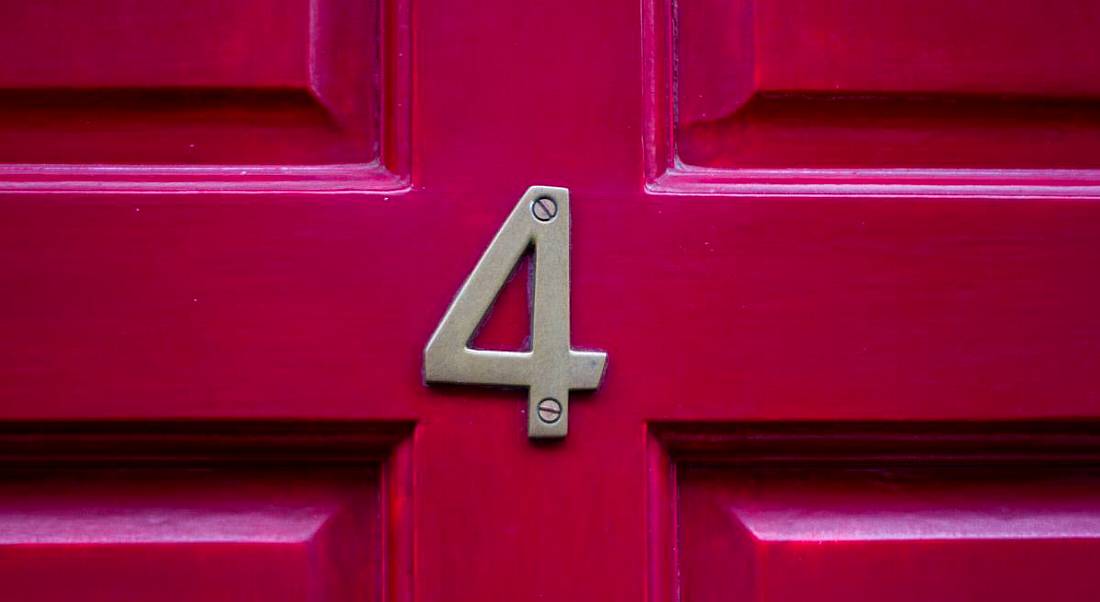 A red front door with a metal number four on it.