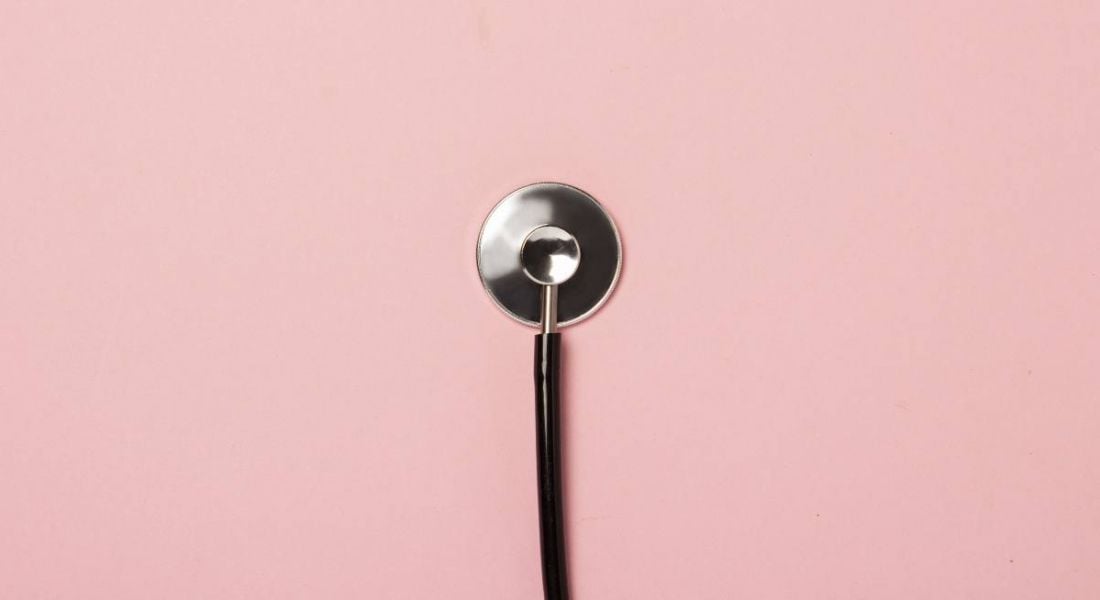 A stethoscope is placed against a pale pink background.