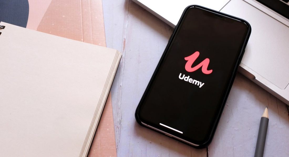 A phone with the Udemy logo on it on an office table.