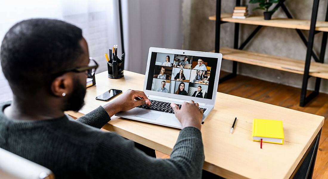 A young professional is starting a new job remotely, talking to his new colleagues on a video call.