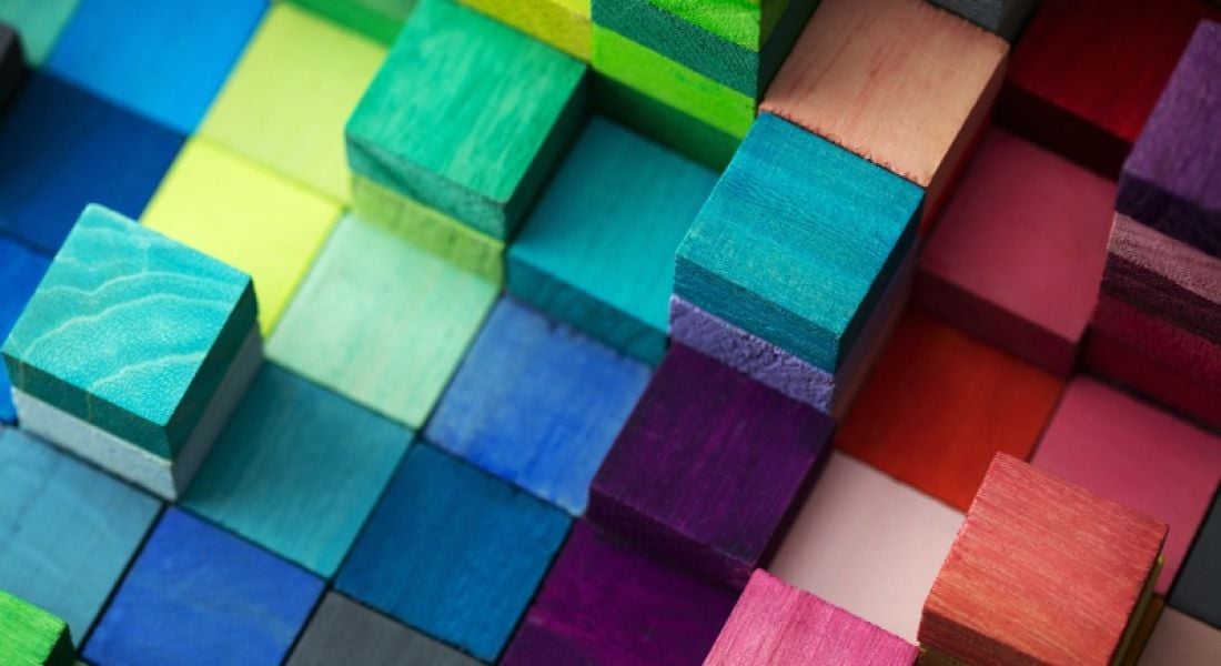 Wooden blocks in many different colours are stacked together.