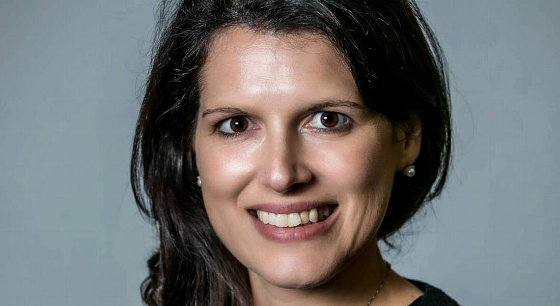 Irene Blat of genomics research company Genuity Science is smiling into the camera against a grey background.