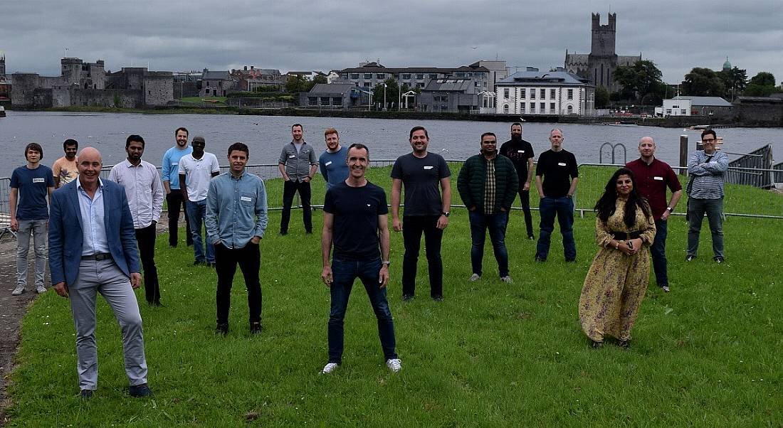 Some of the Transact Campus team standing socially distant from one another on grass with Limerick city behind them.