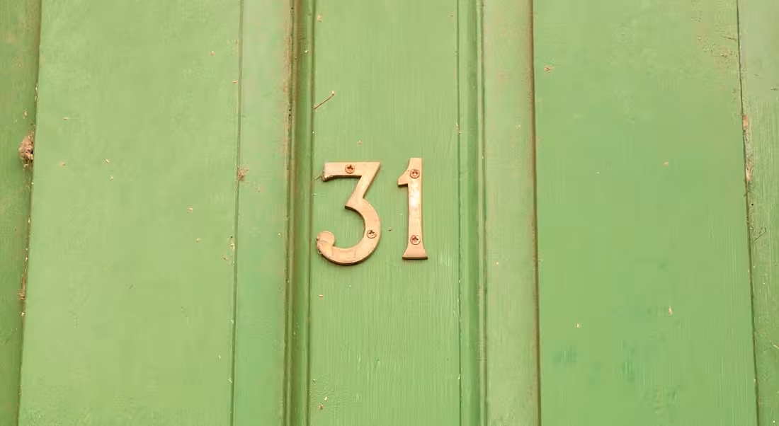 The number 31 in gold against a bright green front door.