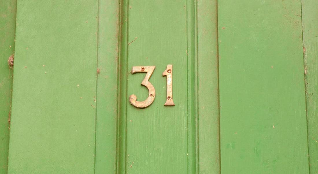 The number 31 in gold against a bright green front door.