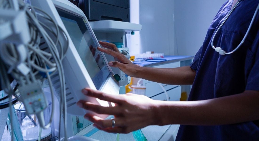 A medical professional using a piece of tech equipment.