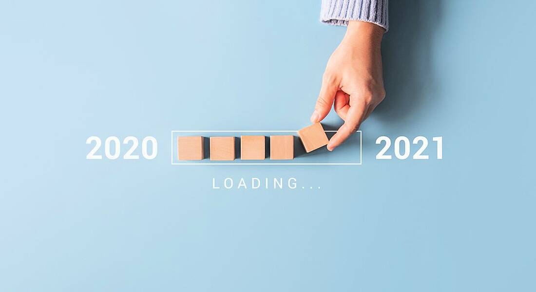 A person's hand is placing wooden blocks in a loading bar shape, moving from 2020 to 2021.