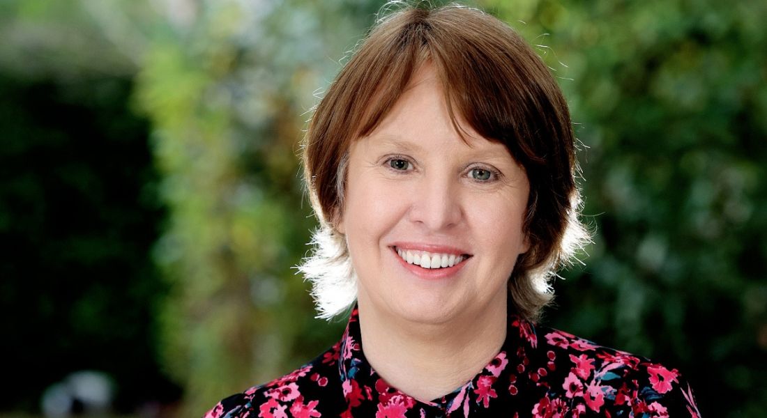 A close-up headshot of Ger Twomey from PwC smiling at the camera outdoors. There is out-of-focus greenery behind her.