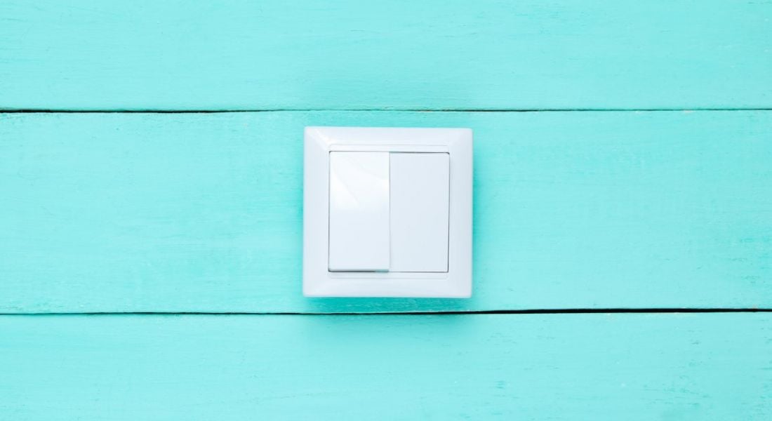 White light switch on a bright blue wooden wall, symbolising the right to disconnect.