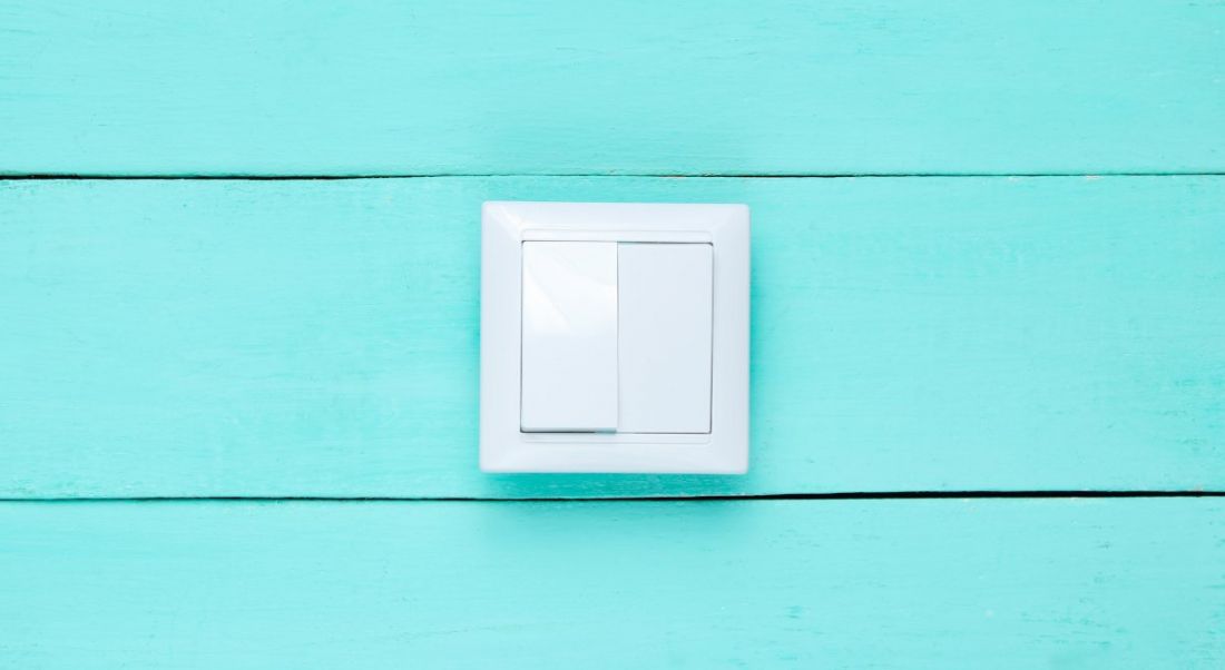 White light switch on a bright blue wooden wall, symbolising the right to disconnect.