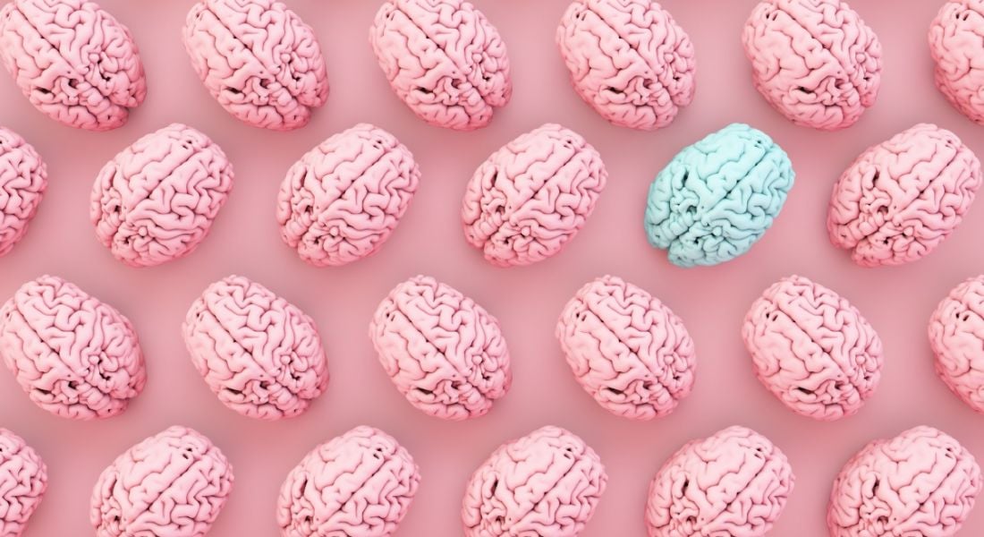 Pink brains are laid out in rows with one blue brain among them against a pink background.