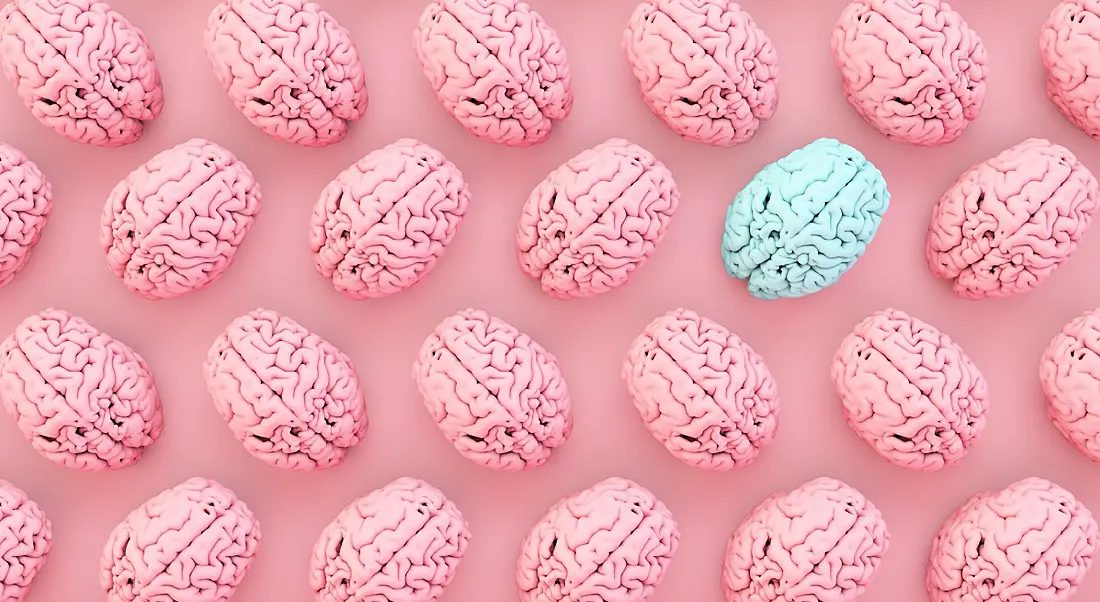 Pink brains are laid out in rows with one blue brain among them against a pink background.