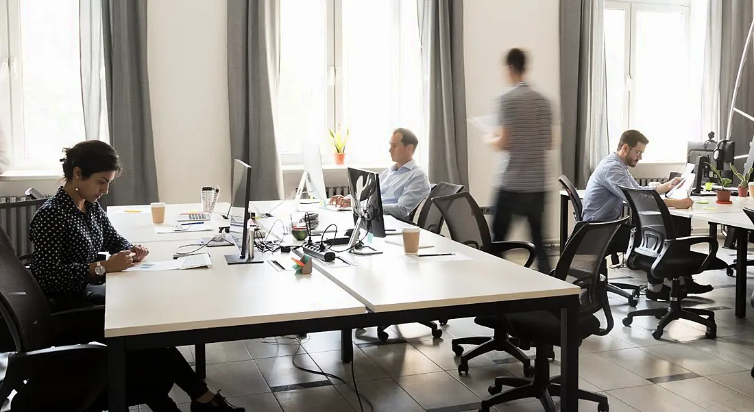 A group of colleagues working together in an office with workplaces returning.