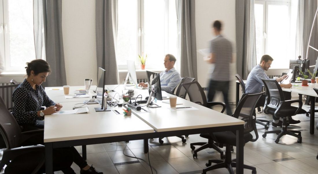 A group of colleagues working together in an office with workplaces returning.