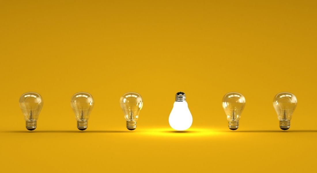 Six lightbulbs are lined up against a yellow background, with one upside down and lit up.