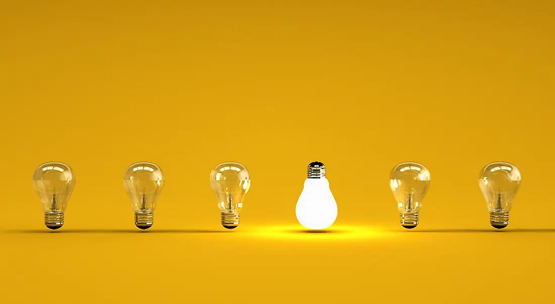 Six lightbulbs are lined up against a yellow background, with one upside down and lit up.