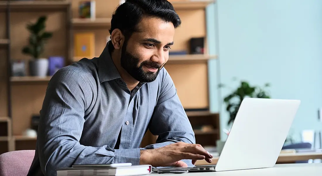 An IT or sales employee is working on his laptop at home.