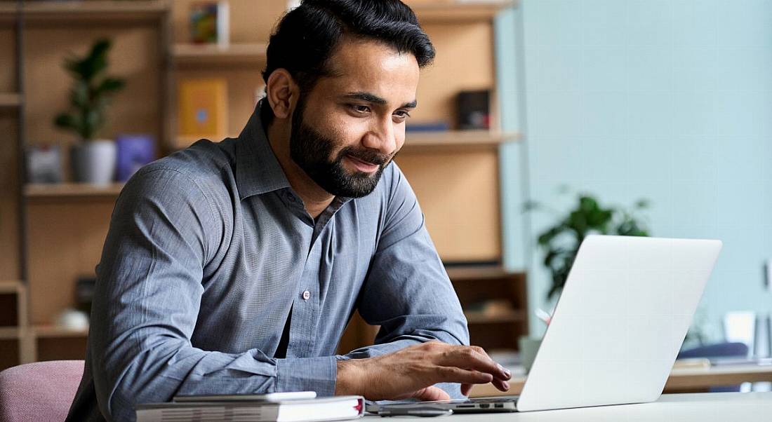 An IT or sales employee is working on his laptop at home.