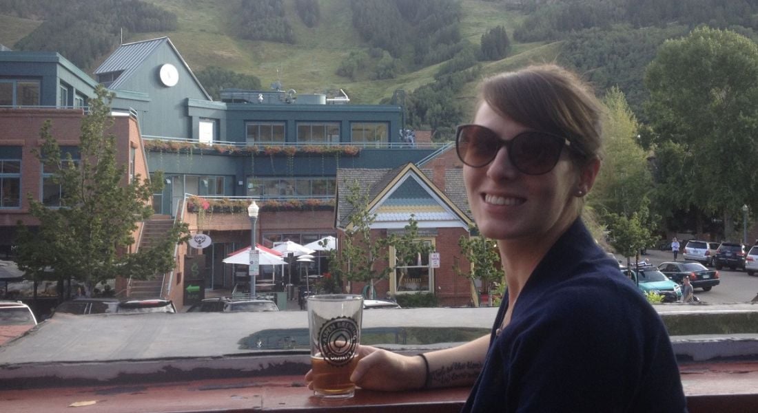 Caitlin Costelle from Genuity Science sits outside a craft brewery enjoying a glass of beer.
