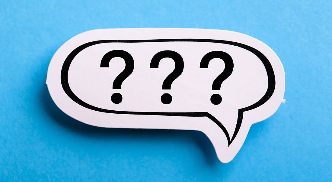 A white speech bubble with three question marks in it is lying against a blue background.