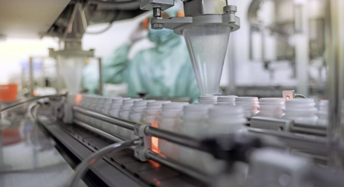 A bioprocessing facility showing the transfer of medicine bottles on a conveyor belt in a pharmaceutical setting.