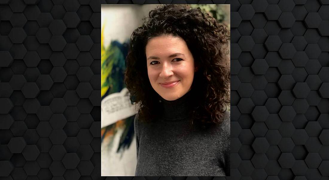 Hannah Herlihy Lowe, head of customer success at Conjura, is smiling into the camera. She has dark curly hair and is wearing a charcoal polo-neck.