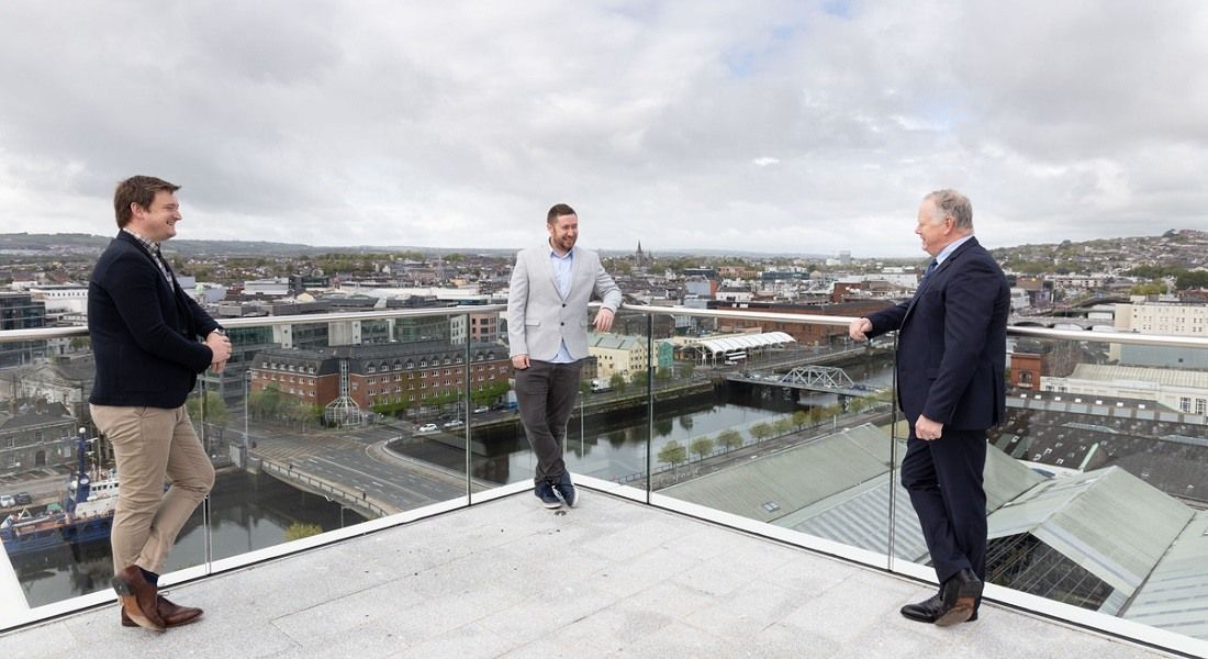 Three men standing on a rooftop in Cork city.