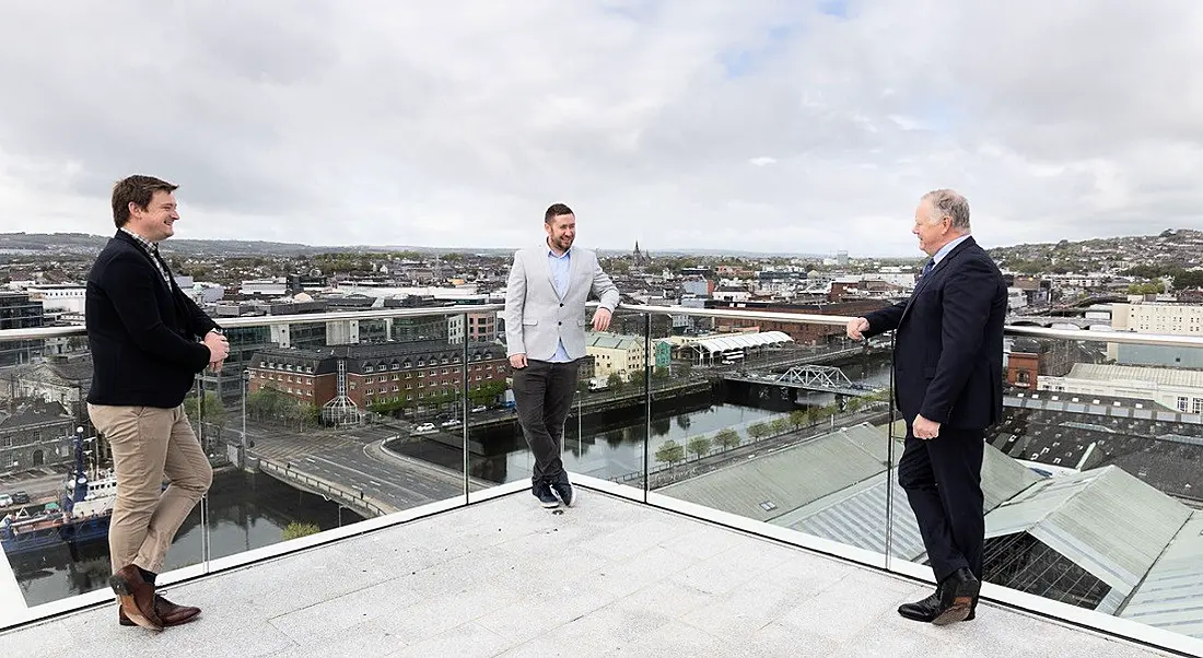 Three men standing on a rooftop in Cork city.