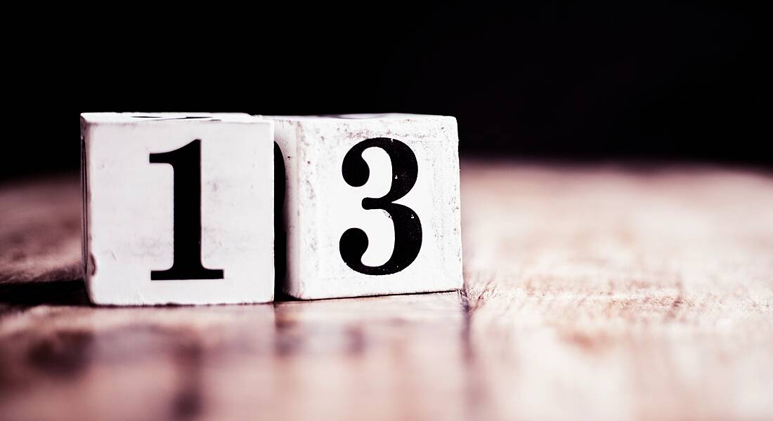 The number 13 written on two wooden blocks sitting on a table.