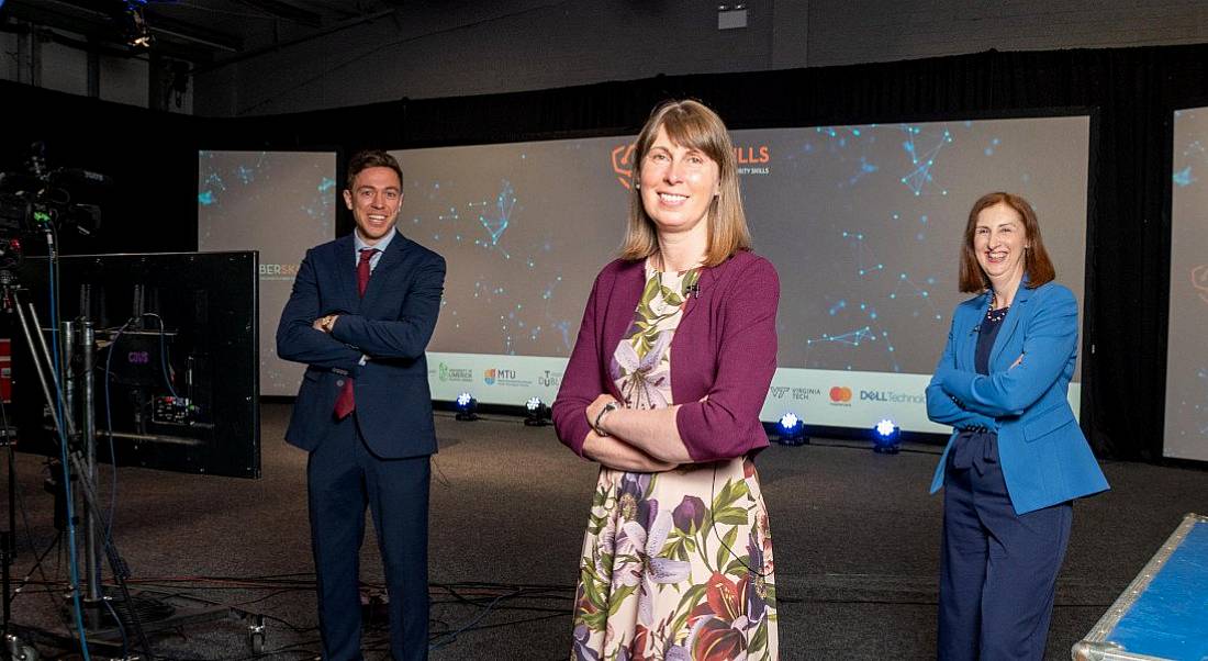 Three people stand socially distanced in a dark room.