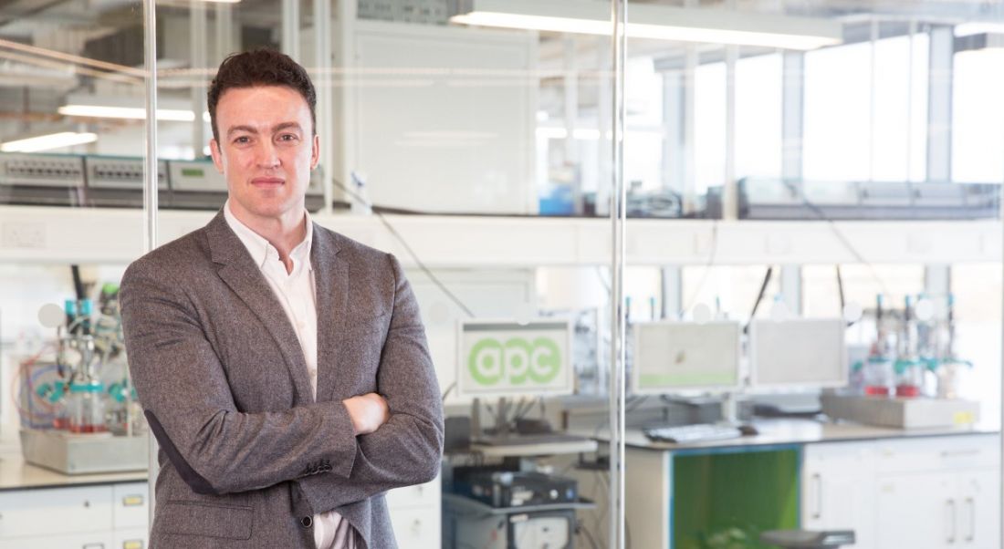 Mark Barrett stands in a suit in an APC pharma lab.